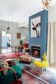 Living room in colourful eclectic style with blue-painted chimney breast