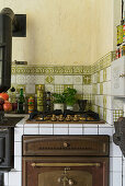 Gas hob and oven in rustic kitchen with green tiles