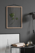 Dried leaves in picture frame on grey wall above side table