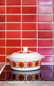 Retro saucepan on stove against red-tiled wall