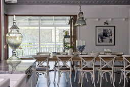 Long dining table and chairs in front of doorway leading onto roofed terrace