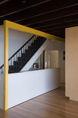 View of staircase in open-plan interior with yellow-painted joist