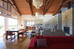 Rotes Polstersofa, Lounge und Essbereich vor Terrassentür in offenem Wohnraum
