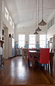 Dining table and kitchen in double-height interior with arched, white wooden ceiling