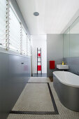 Monochrome modern bathroom in grey and white with bathtub and small sink