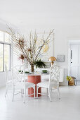 Large arrangement of branches on round table in white dining room