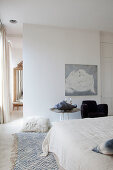 White bedroom with pale blue accents and black armchair