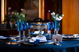 Blue glasses, plates and flowers on festively set table