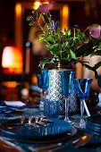 Blue glasses and plates and vase of flowers on festively set table