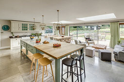 Landhausküche und Sitzbereiche in Wohnraum mit Oberlichtern und Glasschiebetüren zur Terrasse