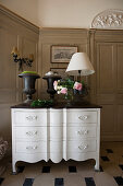 Urns, table lamps and vase of roses on white, antique chest of drawers