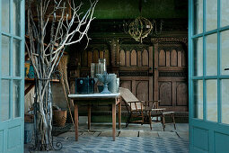 View through open double doors into summerhouse with antique gardening equipment
