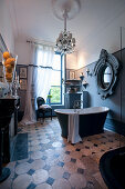 Free-standing bathtub, grand mirror and chandelier in antique-style bathroom