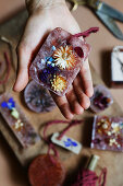 Hand holding handmade scented wax with dried flowers
