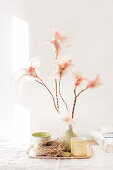 Frühlingsdeko in Pastell mit Federn an Zweigen, Nest und Keramik