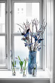 Blumen und Weidenkätzchen mit Papierschmetterlingen am Fenster