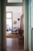 Blick vom Flur in rosafarbenen Wohnraum mit Vintage-Schaukelstuhl und Stehlampe