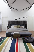 Double bed, bedroom bench and striped rug in loft apartment