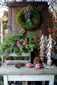 Christmas decoration with a moss wreath, box with branches, wooden decorative trees, and rose hips