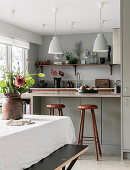 Dining table in front of open-plan kitchen in earthy shades