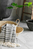 Striped cotton towel in basket next to bathtub