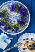Kranz aus Anemonen auf blauem Teller, Heidelbeeren und Kreide