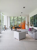 Grey sofa set and dining table in open-plan interior with glass walls