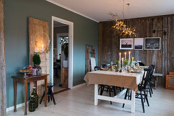 Set table below chandelier made from branches in dining area with board wall