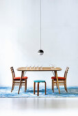 Designer-Kugellampe über Holztisch mit Holzstühlen und Hocker