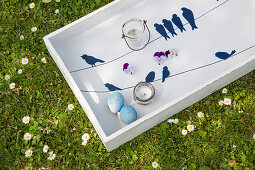 White wooden tray decorated for Easter with blue bird motifs