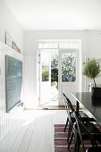 Black table in white dining room with double doors leading to garden