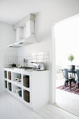White, masonry kitchen base units with integrated gas hob and view into dining room