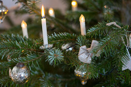 Echte Kerzen und Lichterkette am Weihnachtsbaum mit silberner Deko
