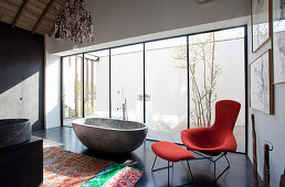Free-standing, stone bathtub and designer armchair in modern bathroom