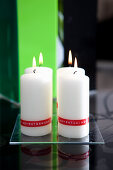 Modern Advent arrangement of labelled pillar candles on glass plate