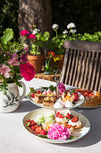 Pastries, fruit and flowers on cake stand in summery garden