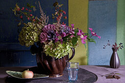 Bouquet of hydrangeas, clematis, roses, astilbes and spindle fruits in farmhouse jug