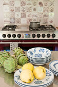 Quinces, artichokes and plates on stainless steel table in kitchen