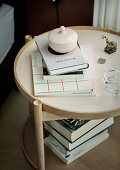Books and porcelain pot with lid on round bedside table
