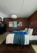 Cushions and bedspread on double bed in bedroom with brown walls