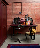 Desk and chairs against dusky pink brick wall with wooden cupboard on one side