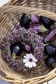 Wreath of flowering thyme, aubergines and flower in basket