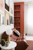 Brown, modern, leather sofa below gallery of pictures and next to shelves