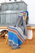 Knitted blanket with Norwegian pattern next to tiled stove
