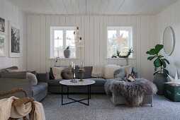 Grey upholstered furniture in cosy living room with wood-panelled walls