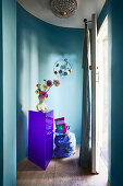 Bust vase on purple pedestal in front of blue curved wall