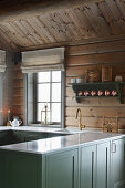 Country-house kitchen with green panelled cabinets in log cabin