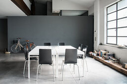 Double table and chairs in industrial loft apartment with bicycle against grey wall in background