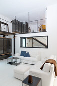 White sofas in living area and view of gallery in industrial-style loft apartment