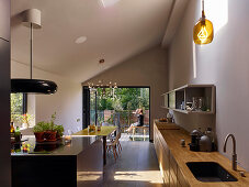 Open-plan kitchen, dining table and access to garden in modern interior